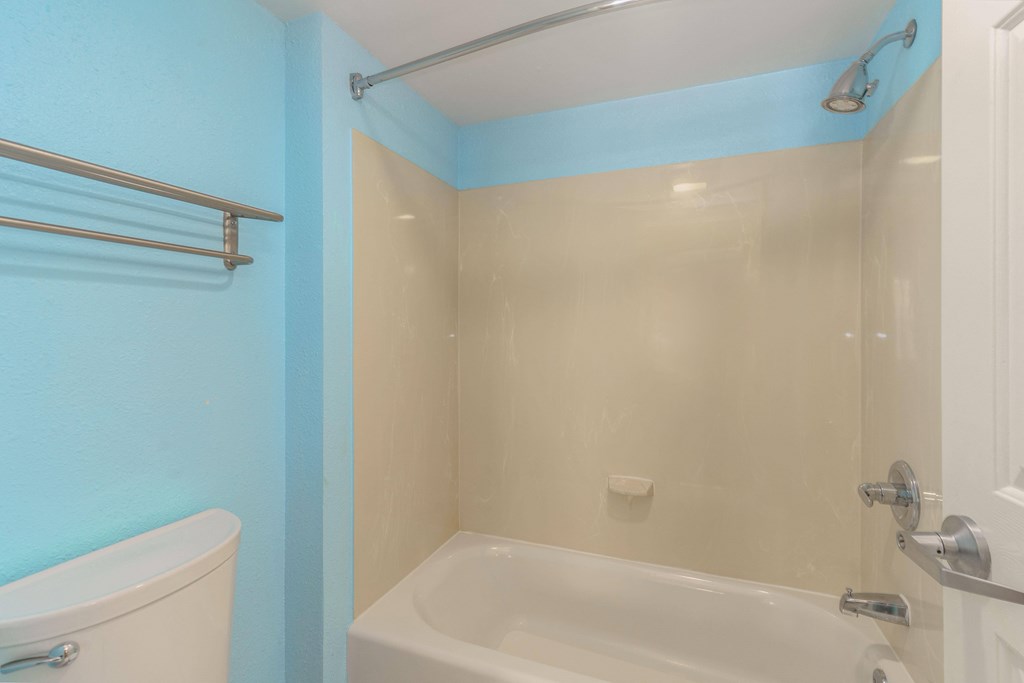 a bathroom with blue walls and a white toilet and shower